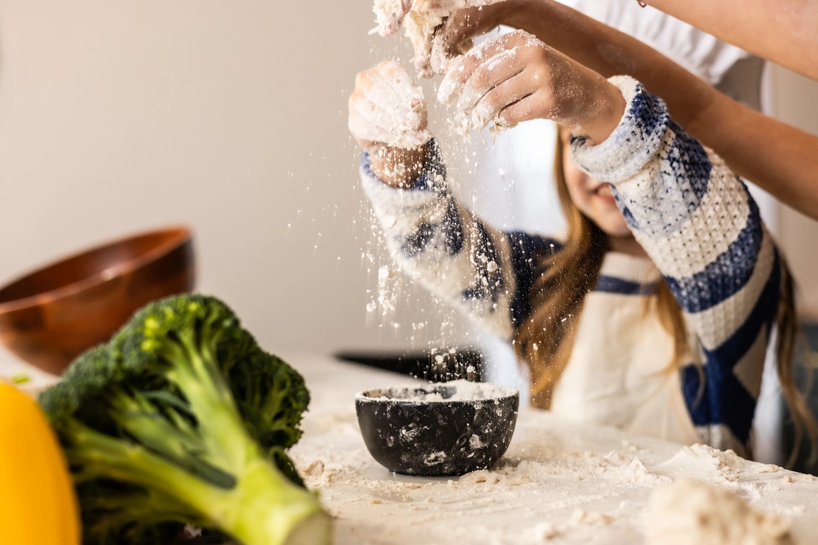 Child sprinkling flour in a kitchen