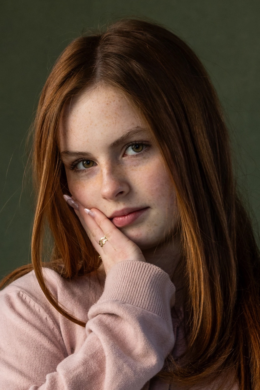 Portrait of a red-haired young woman resting her face on her hand