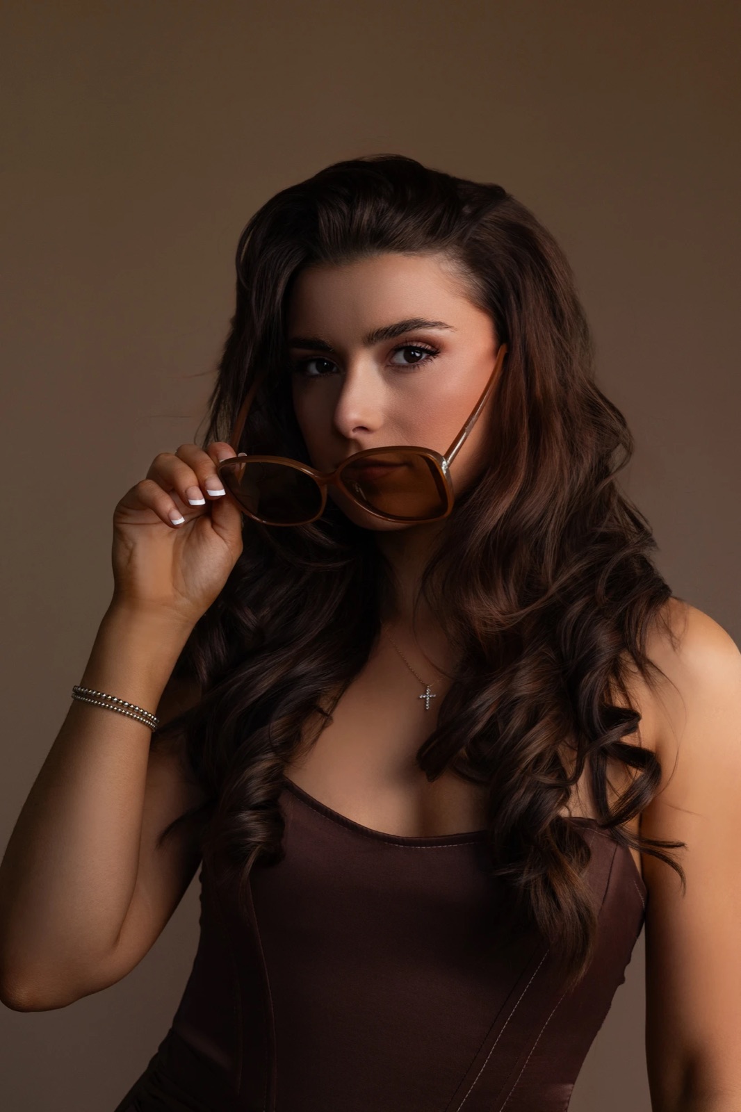 Studio portrait of a woman lowering brown sunglasses